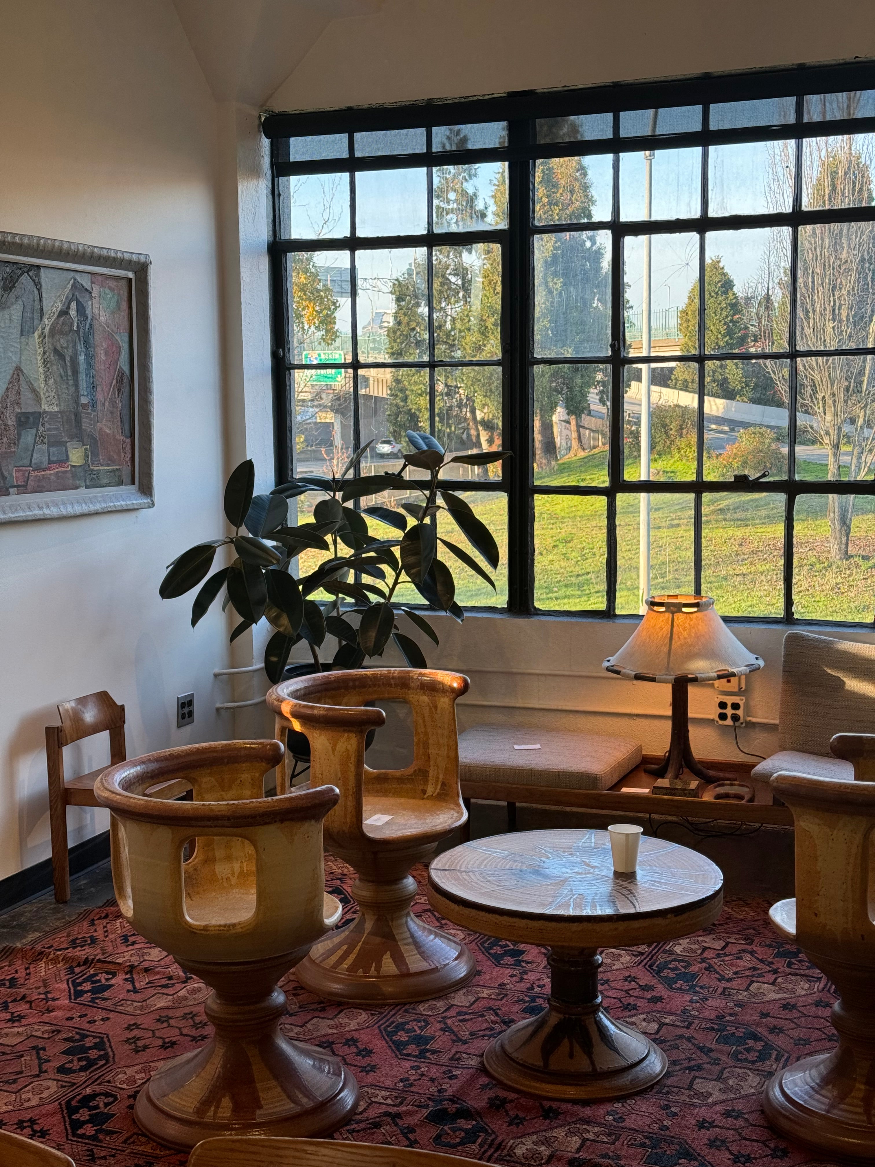 Room with a large window, round table, chairs, and a plant.